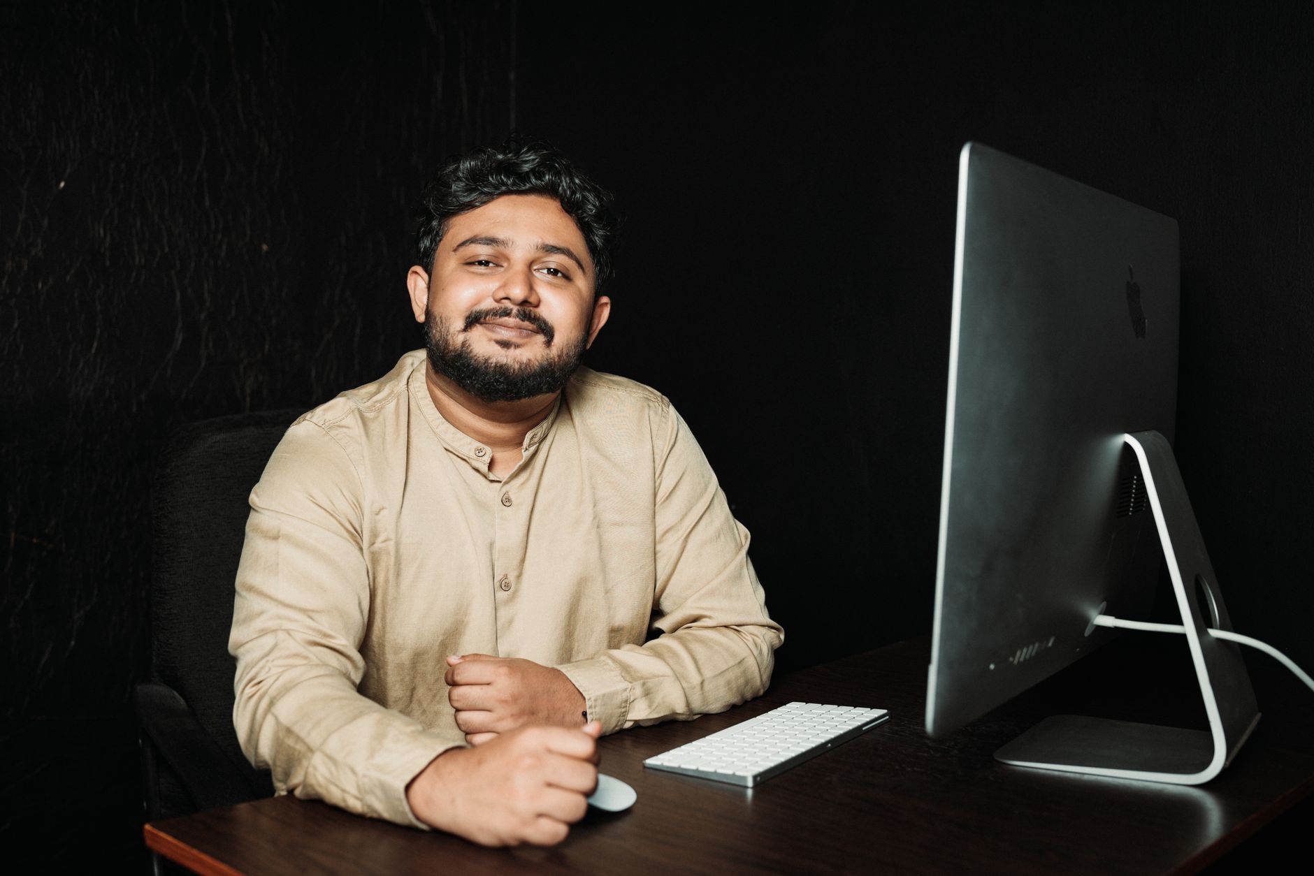 Kantoormedewerker glimlacht achter een computerscherm in een sfeervol verlicht kantoor.